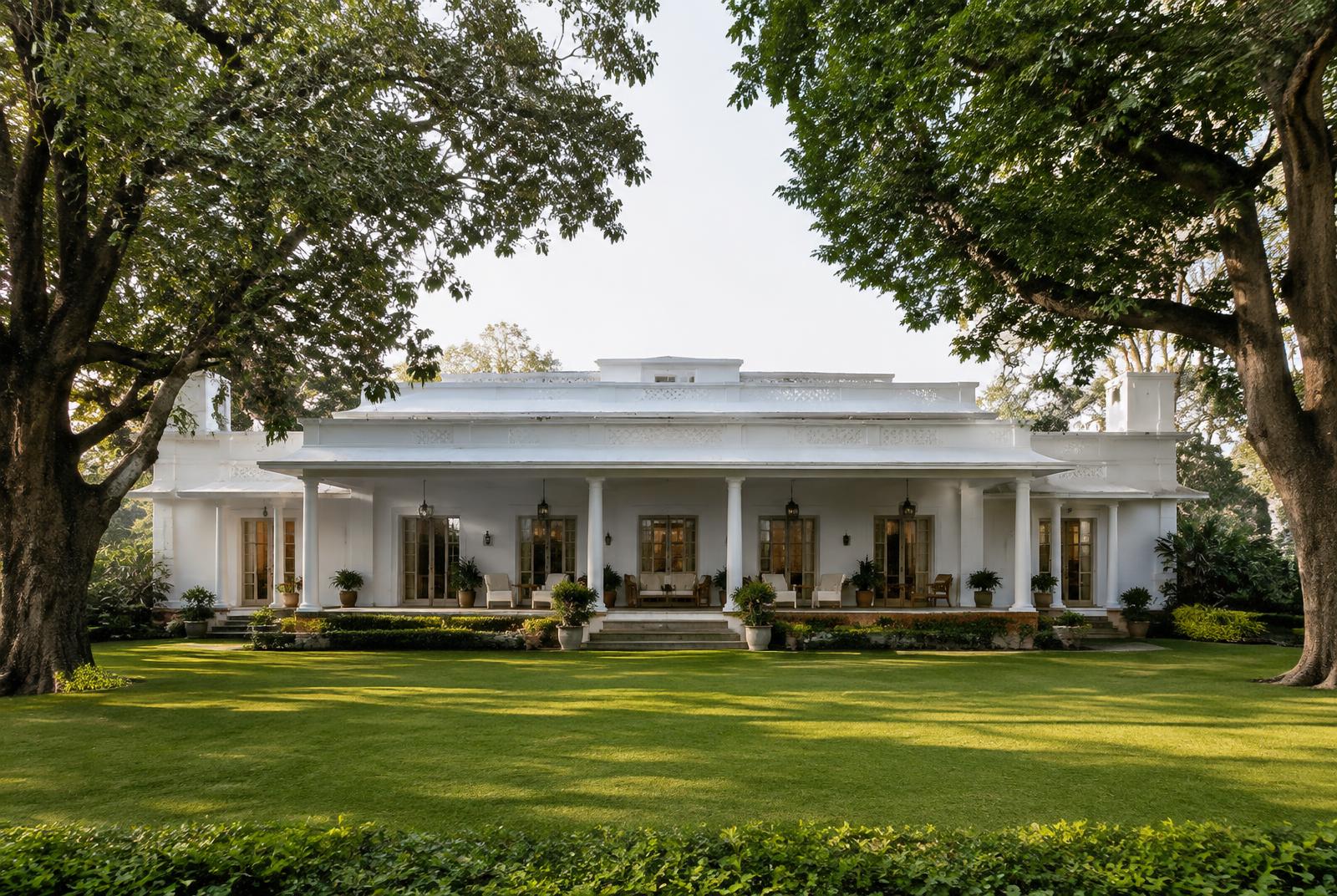 White colonial bungalow with a columned verandah behind a broad lawn